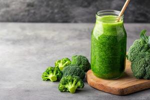 Broccoli juice in glass bottle concept. Fresh green smoothie in jar with broccoli on wooden board. photo