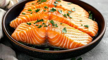 Salmon fillet with crispy skin concept. Fresh salmon fillets garnished with herbs in a dark bowl. photo