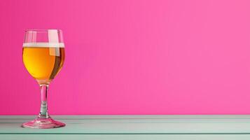 A glass of golden drink rests on a pastel-colored surface against a vibrant pink background. photo