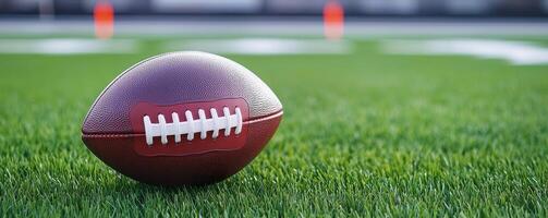 A close-up of a football resting on vibrant green grass, highlighting its textured surface and stitching against a blurred field background. photo