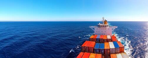 A cargo ship navigates through a vast ocean, showcasing colorful containers against a clear blue sky. photo