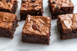 Rich brownie with chocolate chunks concept. Decadent chocolate brownies with a glossy top and fudgy texture, arranged neatly on a marble surface, inviting indulgence. photo