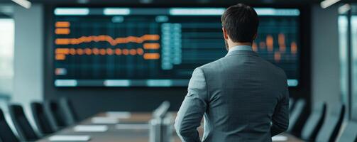 A businessman observes data on a digital screen in a modern conference room, emphasizing analytics and decision-making in a corporate environment. photo