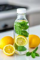 Self-care routines for Wellness concept. A bottle of infused water with lemon slices and mint leaves, surrounded by whole lemons on a bright countertop. photo