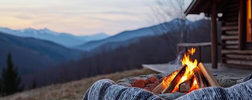 Girlfriend getaways for travel concept. Cozy campfire burns in the foreground, with a rustic cabin nearby and majestic mountains in the background, creating a serene outdoor atmosphere at dusk. photo