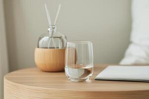 Self-care routines for Wellness concept. Glass of water, a decorative diffuser, and a notebook on a wooden surface, creating a calming atmosphere. photo