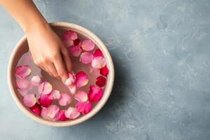 Self-care routines for Wellness concept. A hand gently touches rose petals floating in water, creating a serene and soothing atmosphere. photo