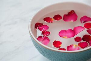 Self-care routines for Wellness concept. Bowl filled with water and vibrant pink rose petals, creating a calming and decorative ambiance. photo