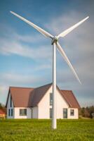 Home improvement with sustainable building concept. Wind turbine stands in front of a contemporary house on a grassy field, showcasing renewable energy in a picturesque landscape. photo