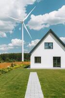 Home improvement with sustainable building concept. White house with a wind turbine nearby, set against a backdrop of blue skies and greenery, emphasizing sustainable living. photo
