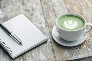 Lifestyle wellness with mental health and self-care concept. Coffee cup with latte art beside a notepad and pen on wooden table. photo