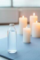 Lifestyle wellness with mental health and self-care concept. Clear bottle of water next to lit candles on a soft surface. photo