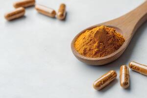 Health supplements and natural remedies concept. Spoon of herbal powder and capsules on a light surface. photo