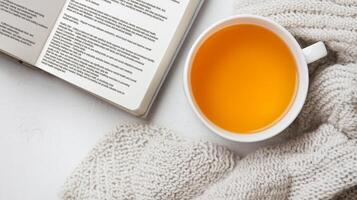 Lifestyle wellness with mental health and self-care concept. Warm tea in a cozy setting with a book and soft knit blanket. photo