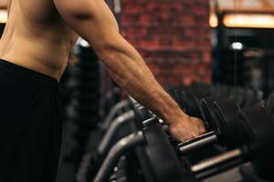 A man is holding a dumbbell in a gym photo