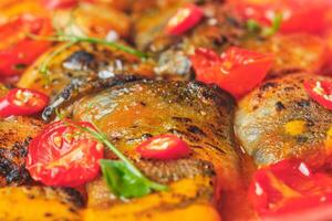 A close up of a dish with fish and tomatoes photo