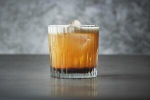 A glass of whiskey sitting on a table. Coctail drink photo