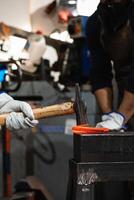 A man is holding an axe while working on a piece of metal photo