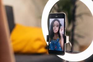 A person taking a selfie with a phone in front of a ring light photo