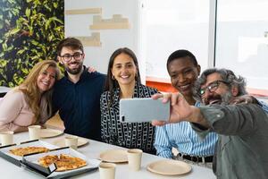 Cheerful multiethnic friends taking selfie during lunch photo