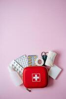 This First Aid Kit is fully stocked with essential supplies and medications, featuring a bright pink background for quick access in health crises when seconds count photo
