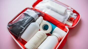 A red first aid kit that is thoroughly filled with various important items such as bottles, bandages, adhesive tape, and several other essential supplies for health and emergencies photo