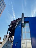 A striking blue building, which features a prominent chimney located on its side, showcases a modern architectural design that notably stands out and enhances the urban skyline photo