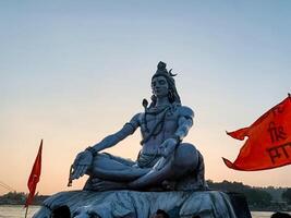 A stunning view of the towering Lord Shiva statue at sunset, adorned with vibrant flags and colors, evokes spirituality, peace, and deep devotion in all who see it photo