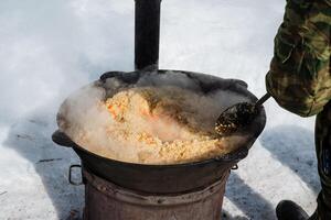 A dedicated person carefully stirs a large pot filled with hearty food, creating a warm and comforting meal that is absolutely perfect for chilly winter days. Enjoy this delightful dish photo