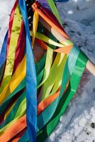 A vibrant and eyecatching bunch of colorful ribbons, showcasing various hues, are elegantly laid out on the pristine snow, making a striking contrast against the bright white background photo