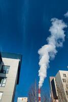 A distinct plume of smoke is billowing out of the chimney placed strategically between two neighboring buildings situated in an urban area, indicating possible activity indoors or pollution photo