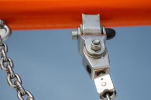 A detailed closeup image showcases a metal pulley system that features a robust chain and an eyecatching orange beam, highlighting its intricate connections and design photo
