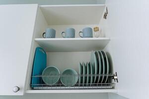The spacious kitchen features a large wooden cabinet that provides ample storage for organizing plates, cups, and a cutting board, enhancing functionality for cooking tasks photo