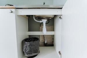 Located conveniently beneath the sink inside the cabinet, there is a trash can that serves the purpose of keeping the area organized and promoting cleanliness throughout the space photo