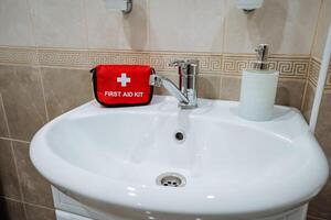 Inside a bathroom, there exists a sink which has a first aid kit positioned conveniently right on top of it, ensuring easy access to essential medical supplies whenever they are needed most photo