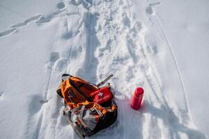 A backpack and a first aid kit are resting on the cold snow, which creates a picturesque scene in the winter landscape, surrounded by the beauty of natures glacial formations photo