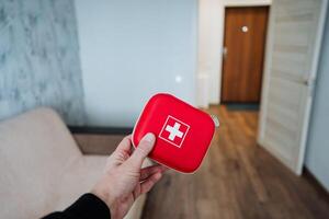 A person is firmly and confidently holding a bright red first aid kit, which is absolutely essential for providing crucial medical assistance during emergencies when it is needed the most photo