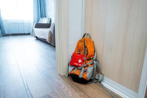 A cozy living room feels warm and inviting, with a sturdy backpack, equipped with a first aid kit, leaning against the wall for reassurance and safety for all guests and family photo