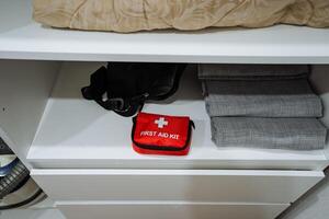 A bright red first aid kit is prominently sitting on a shelf that is conveniently located next to a neatly arranged stack of fluffy towels, ready for immediate use when needed photo