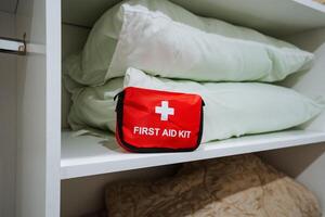 A first aid kit is thoughtfully and conveniently placed on a shelf next to soft, comfortable pillows, ensuring easy access for anyone in case of unexpected emergencies that may arise photo