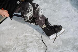 A skater gets ready on the ice rink, donning stylish black ice skates and cozy snowy pants for an exhilarating time filled with thrill and enjoyable exercise activities photo