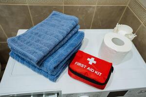 A first aid kit is conveniently placed on top of a washing machine, right next to a roll of toilet paper, making it easily accessible for any emergencies or personal care needs photo