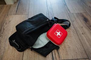 A first aid kit is conveniently located next to a black bag, which may serve as either luggage or a personal item, ensuring quick and easy access during emergencies when needed photo