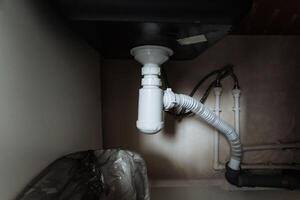 In a cramped, dimly lit room, there is a sink that sits with a drain pipe directly below it, which is essential for effective wastewater disposal within the plumbing system photo