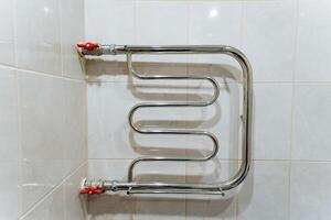 In a beautifully designed bathroom, a sturdy towel rack is elegantly hanging on a tiled wall, providing a convenient place to hang towels for easy access and drying purposes photo