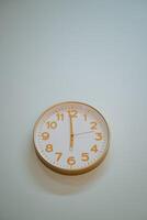 A beautifully designed round clock placed upon a spotless white wall shows that the time is swiftly approaching 500 PM, indicating that the day is gradually shifting into the evening hours photo