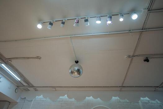 A sparkling disco ball is elegantly hanging from the ceiling of a vibrant room, reflecting light in a dazzling array of colors across the walls and floor, enhancing the ambiance photo