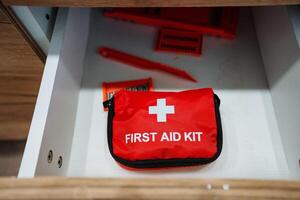 A red first aid kit is located inside a drawer, ready to be used in case of emergencies, ensuring that essential medical supplies are easily accessible when they are needed most photo