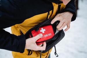 An individual is meticulously and thoughtfully placing a first aid kit into their pocket for quick and easy access in case of emergencies or injuries while out and about on the go photo