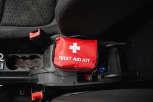 A red first aid kit is conveniently positioned in the center console of a car, ensuring that it is easily accessible in case of any minor injuries or emergencies while driving photo